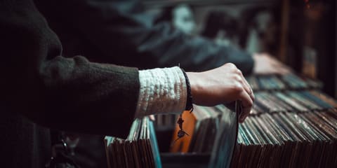 Une main feuillette une rangée de disques vinyles dans un magasin de musique